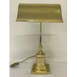 A modern brass desk lamp with swan neck on a pedestal base.