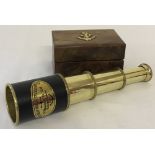 A small 3 draw brass telescope in a wooden box with brass anchor motif.