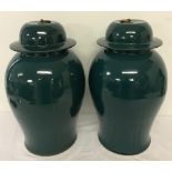 A pair of green ceramic oriental temple jars with brass ring shaped finials to lids.