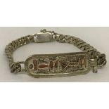 A white metal hieroglyph identity bracelet with curb chain. Indistinct mark to clasp.
