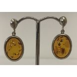 A pair of oval white metal and Baltic amber drop earrings. Butterfly backs marked 925.