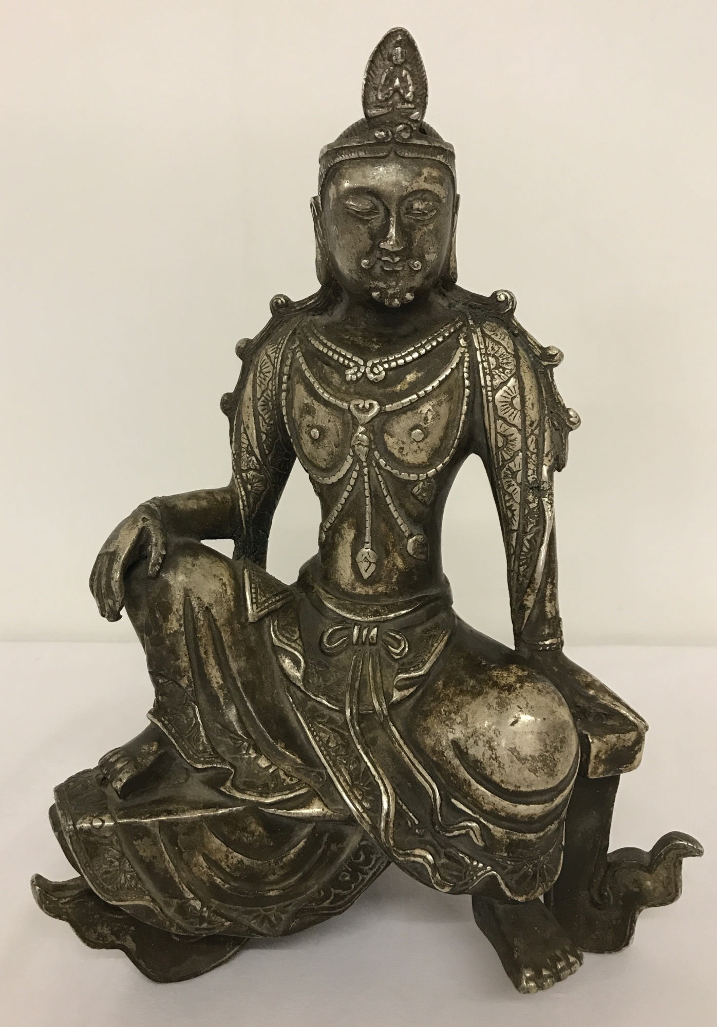 A white metal figurine of an Oriental Deity.