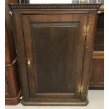 An antique dark oak corner cupboard. 3 interior shelves with curved fronts.