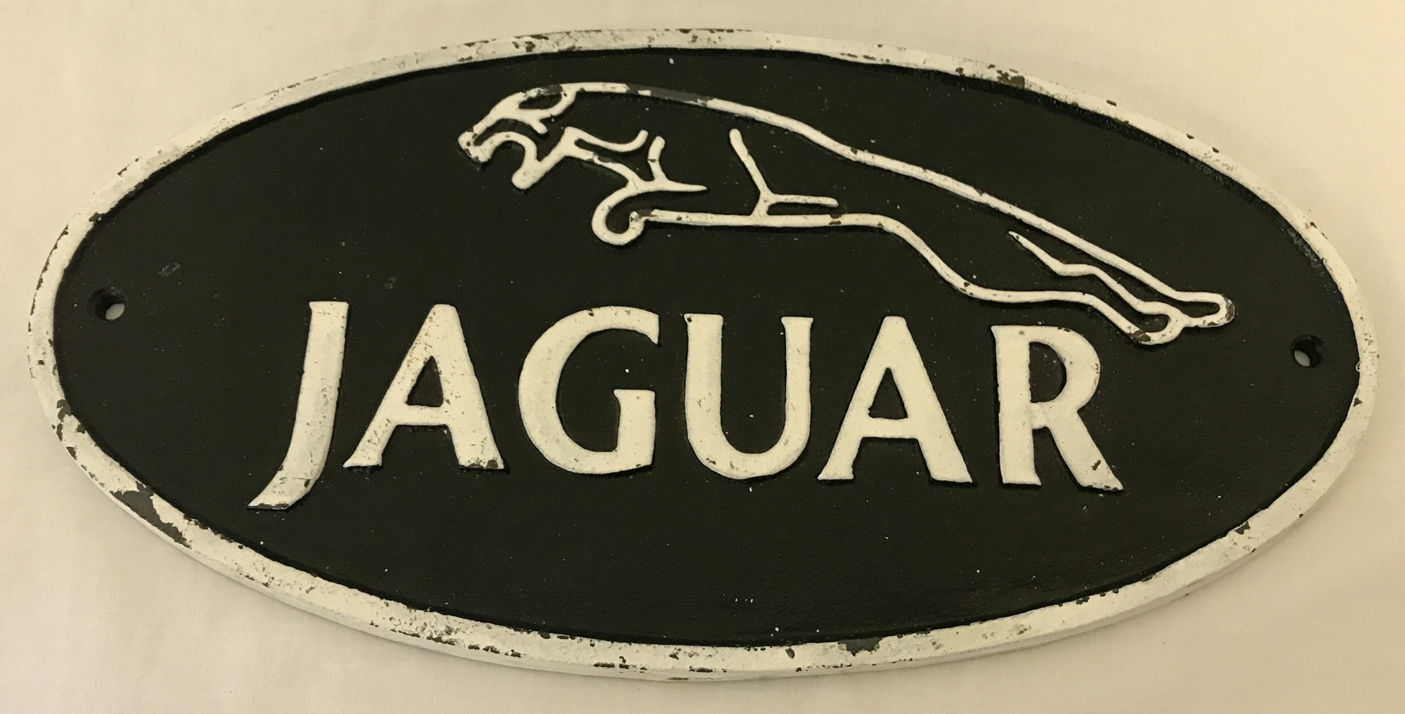 A painted cast iron, oval shaped, Jaguar wall plaque with fixing holes.