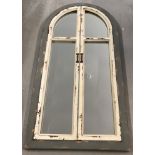 A heavy, large wooden framed mirror in the shape of a curve topped door.