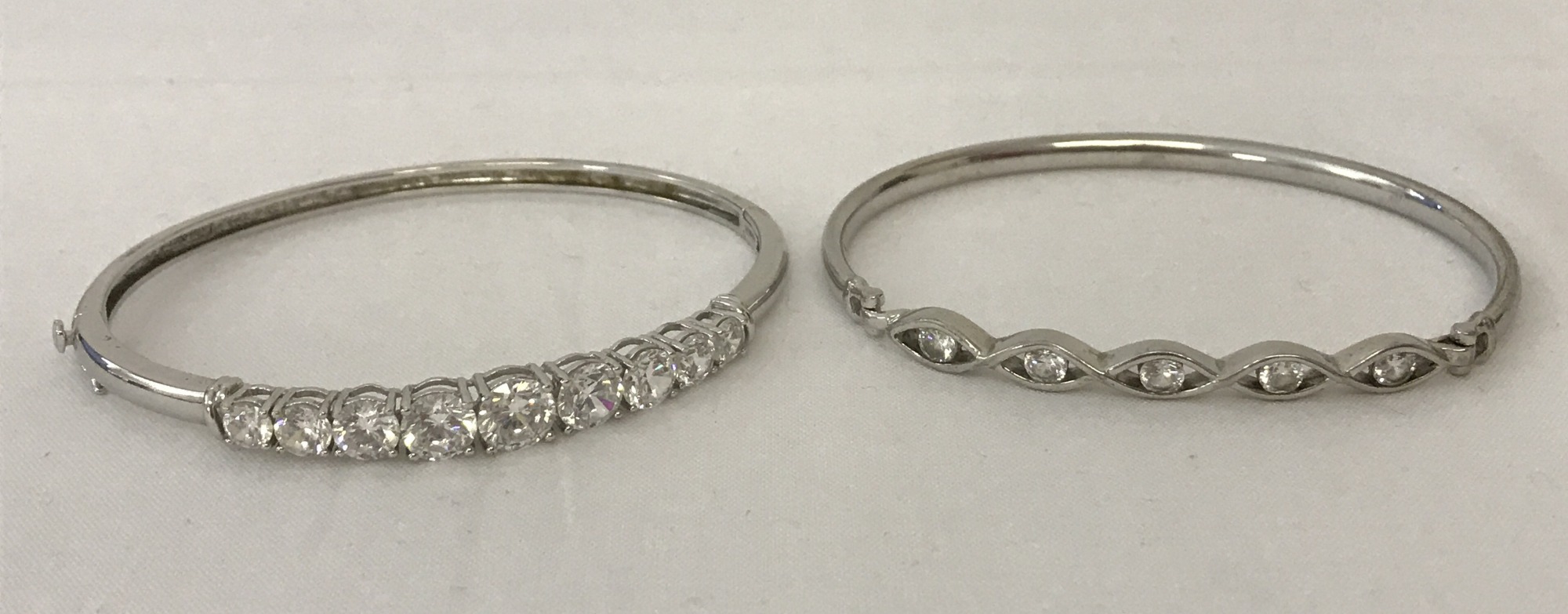 2 ladies silver bangles both set with cubic zirconia stones.
