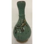 A green speckled glaze vase with a lizard detailed in relief.