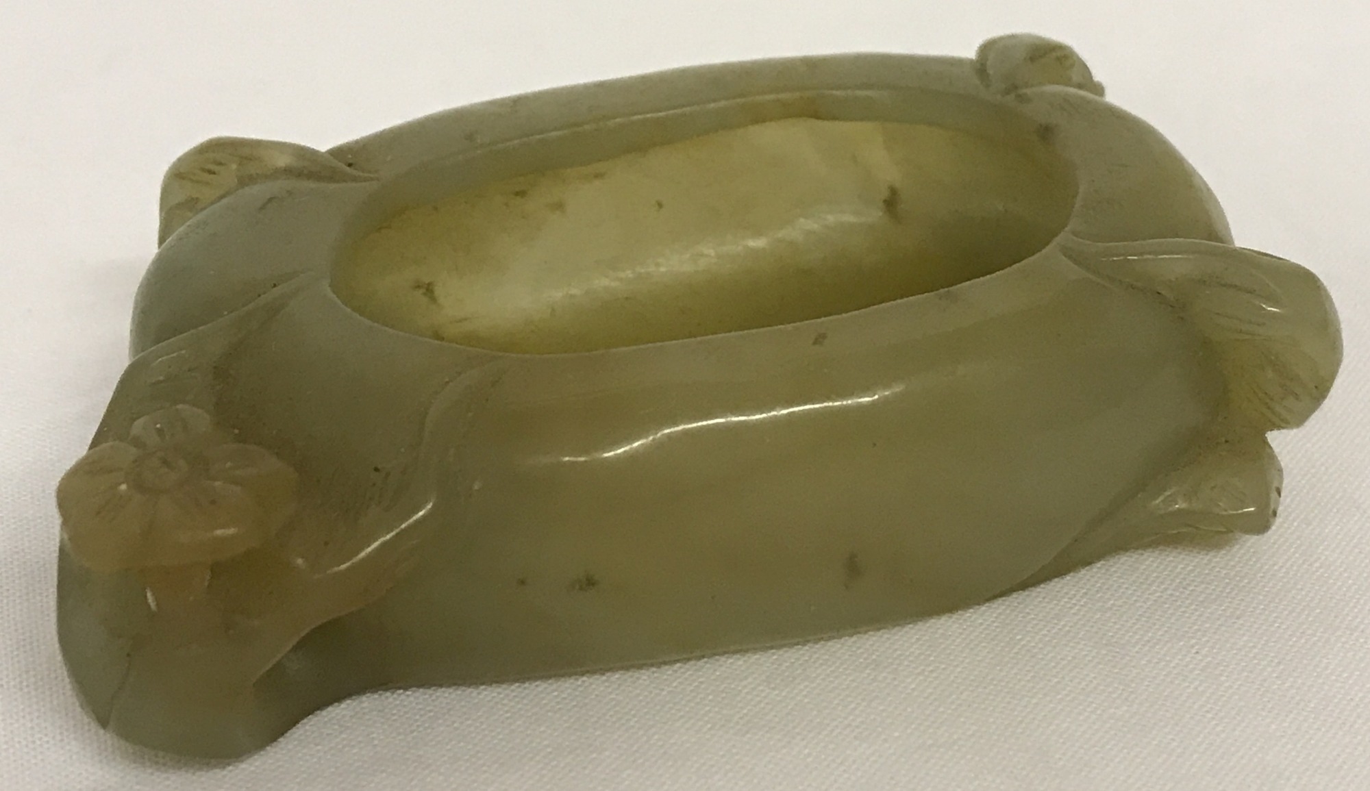 A carved jade brush washer with floral detail.
