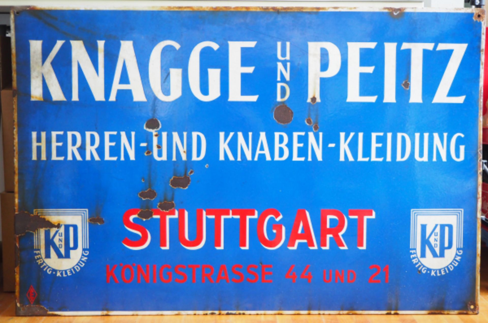 Emailschild Knagge und Peitz - Stuttgart.Blauer Grund, weiße und rote Schrift, mit Firmenlogo,