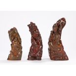 Three polished horn carvings depicting a mother and child and two smiling gentlemen, the largest