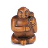 Japanese Meiji period netsuke, the wood netsuke depicting a naked seated boy holding a lotus, with