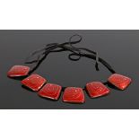 Enamel necklace, with six panels with a deep red ground and swirl centre with random white squares