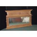 Pine framed overmantel mirror, with stepped pediment above a scroll and mask carved panel and shelf,