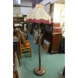 Mahogany standard lamp with tasselled shade and turned stem on a circular plinth base