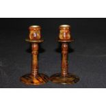 Pair of tortoiseshell effect candlesticks, with shaped sconces and wasted stems on circular bases,
