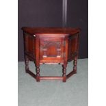 Old Charm oak cupboard, with arched panelled door and flanked by canted panels, raised on turned