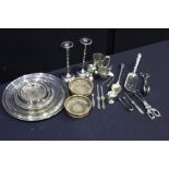 Collection of silver plated items, to include a pair of candlesticks, a basting spoon, tongs,