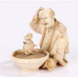 Japanese Meiji period ivory okimono, the okimono carved as a seated man looking with amazement at