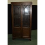 Oak bookcase, with carved pediment above two astragal glazed doors with panelled lower sections,