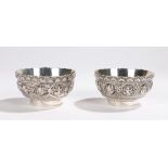 Pair of Oriental white metal bowls, with arch cast rims and bodies with depictions of deities, on