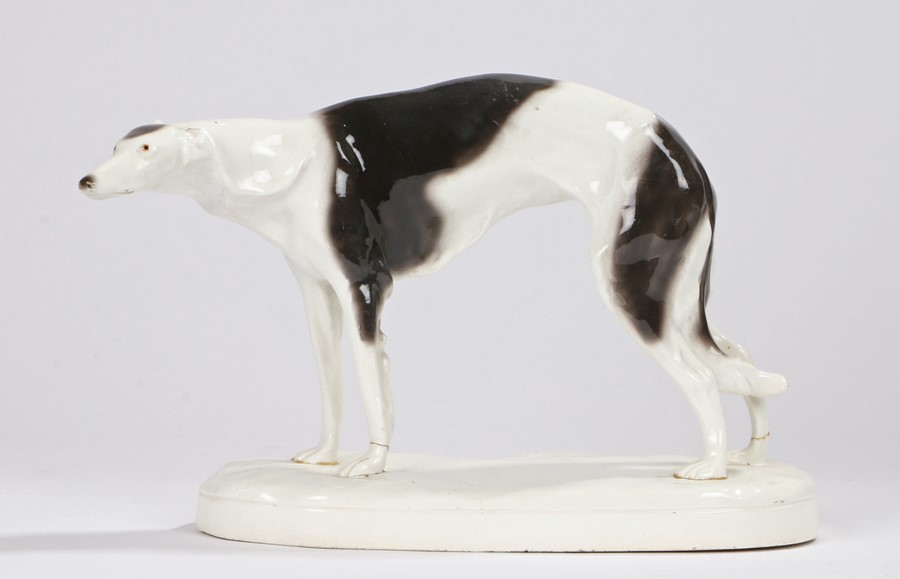 Goldscheider porcelain greyhound, modelled in a standing position, on an oval white plinth base,