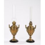 Pair of brass oil lamps, with mask cast handles to the leaf and roundel decorated bodies, raised