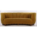 Mid 20th Century curved settee, upholstered in a mustard coloured material, on square chamfered