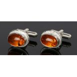 Pair of amber and silver cufflinks, with cabochon cut amber set to the cufflinks