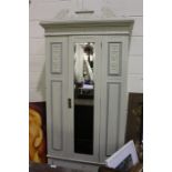 Painted wardrobe, the scrolled pediment above a bevelled mirror door flanked by urn carved panels,