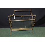 Brass canterbury, with reeded handle above two glass panels, on scrolled end supports and out-