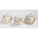 Three Poole pottery biscuit barrels and covers, two with swing handles, with foliate and insect