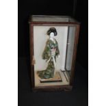 Japanese doll, depicting a geisha in traditional costume with stringed instrument, housed in a glass
