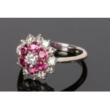 18 carat white gold diamond and ruby set ring, the flower head design with central diamond and a