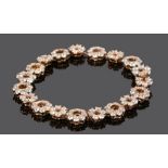 Fine diamond set bracelet, with a row of nineteen diamond set flower heads with pierced centres,