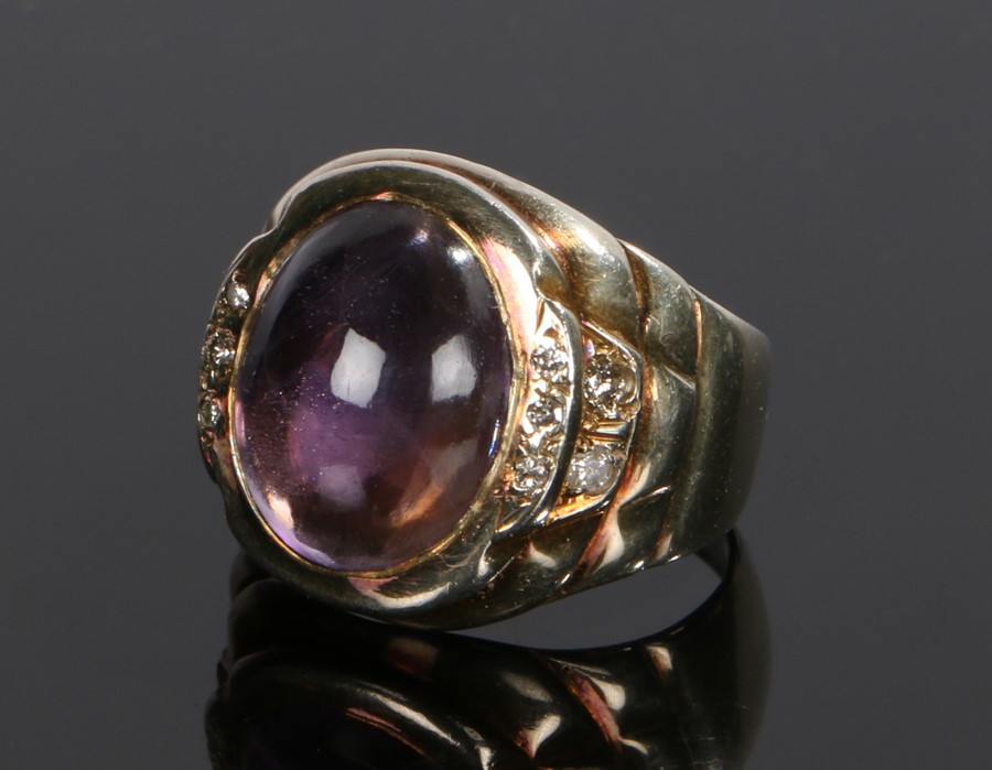 Amethyst and diamond set ring, the central cabochon amethyst flanked by diamonds to the shoulders,