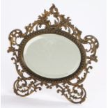 19th Century gilt metal easel mirror, the oval bevelled mirror plate housed in a beaded pierced