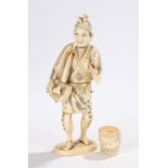 Japanese Meiji period ivory figure of a street musician, the musician carrying a bag and a