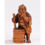 Japanese wood netsuke, carved as a man standing above a container, signed to the base, 5cm high