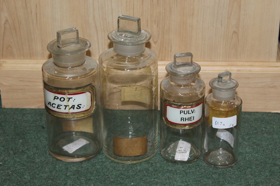 Four glass apothecary jars, three with labels "pulv: rhei", ""pot: acetas", "chloral hydras", the