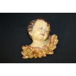 Painted carved wooden cherub head, with gilt leaf decoration