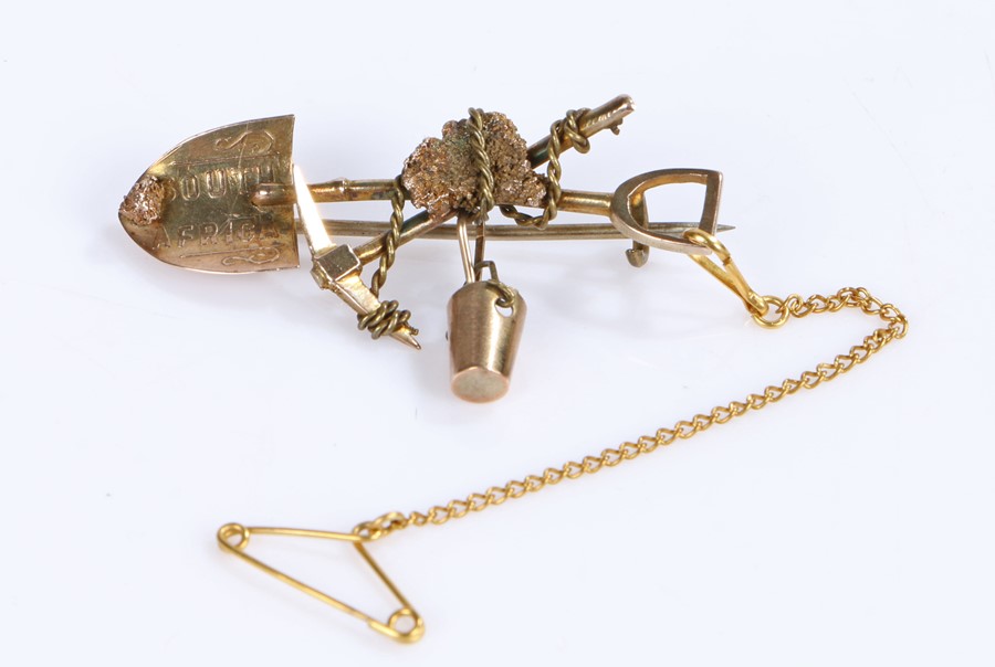 South African gold mining interest, a 9 carat gold brooch with a shovel and pickaxe and a swinging
