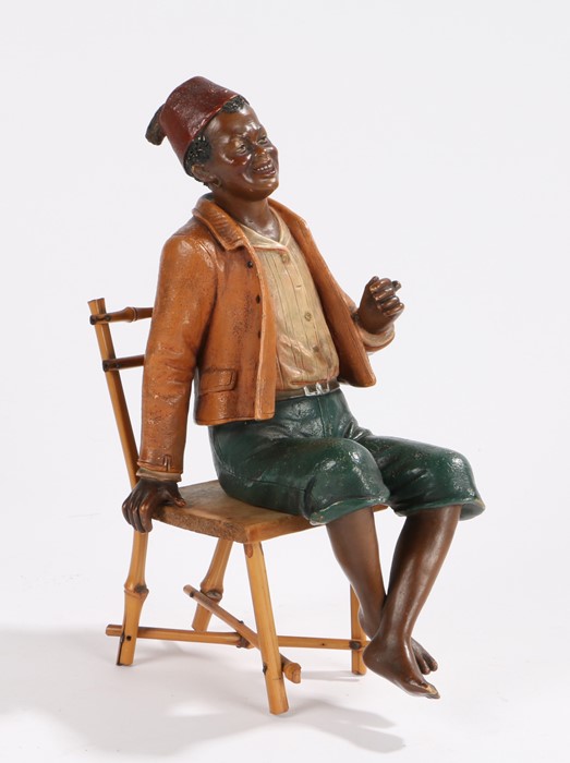 Bloc pottery figure, depicting a gentleman wearing a red fez, seated in a bamboo chair, the figure