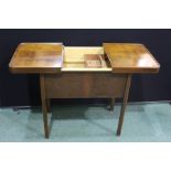 Walnut veneered sewing table, the sliding lid with spring mechanism opening to revealan interior