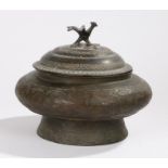 Middle Eastern metal pot and cover, surmounted by a bird above the domed lid and squat body, 25cm