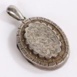 Victorian silver locket, the centre raised and engraved with flowers with scallop edge and above the