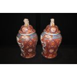 Pair of Oriental Imari design vases, of large size, surmounted by dogs of foo above foliate