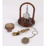 Ingersoll open face pocket watch on a white metal chain and wooden hanging stand, two pound coin