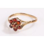 9 carat gold ring, the flower form head with seven garnets on pierced shoulders, ring size Q