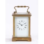 French brass carriage clock, the corniche case with swing handle above an oval bevelled glass
