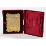 Gilt metal card case, with scroll and foliate decorated exterior, housed in a red velvet and silk